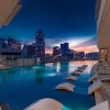 a pool with chairs around it and a city in the background