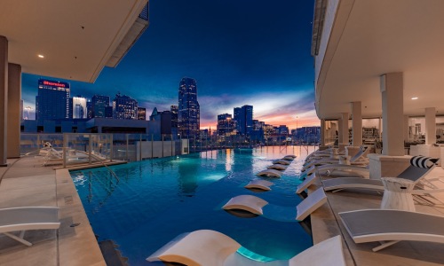 a pool with chairs around it and a city in the background