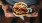 man holds a thick, juicy burger with both hands