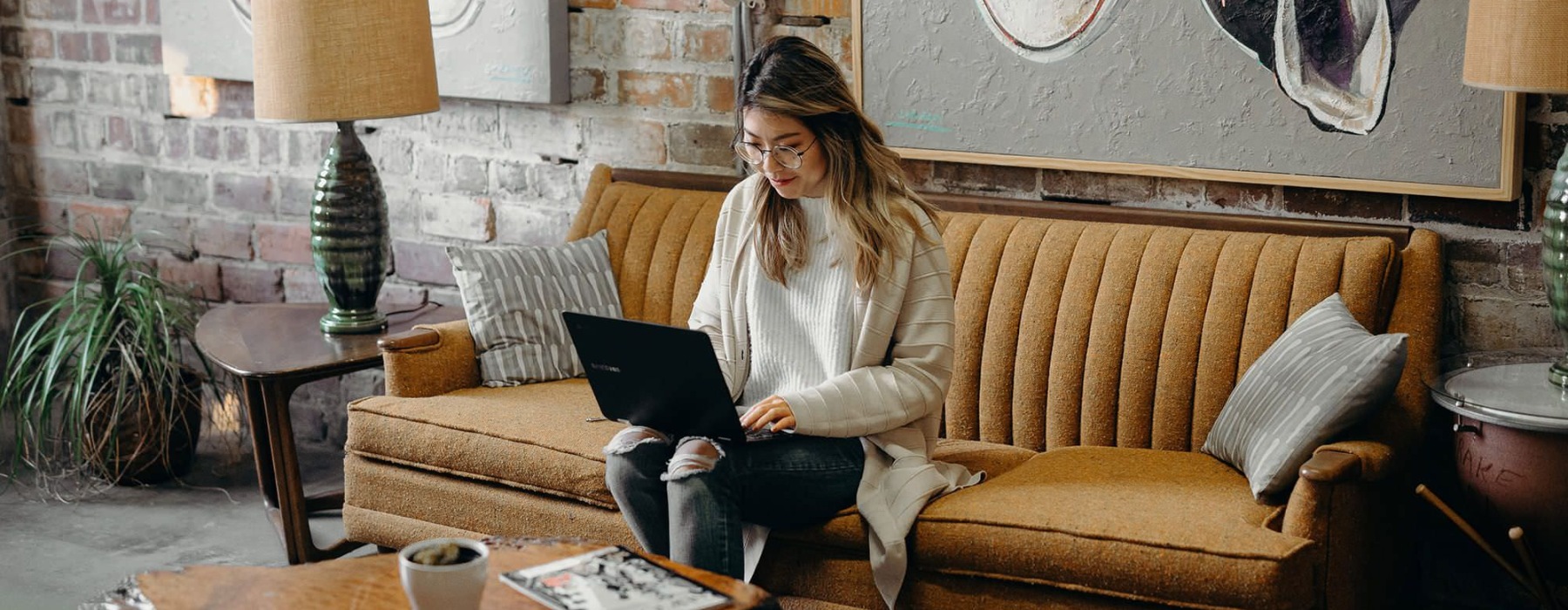 woman sitting on a couch working on a laptop